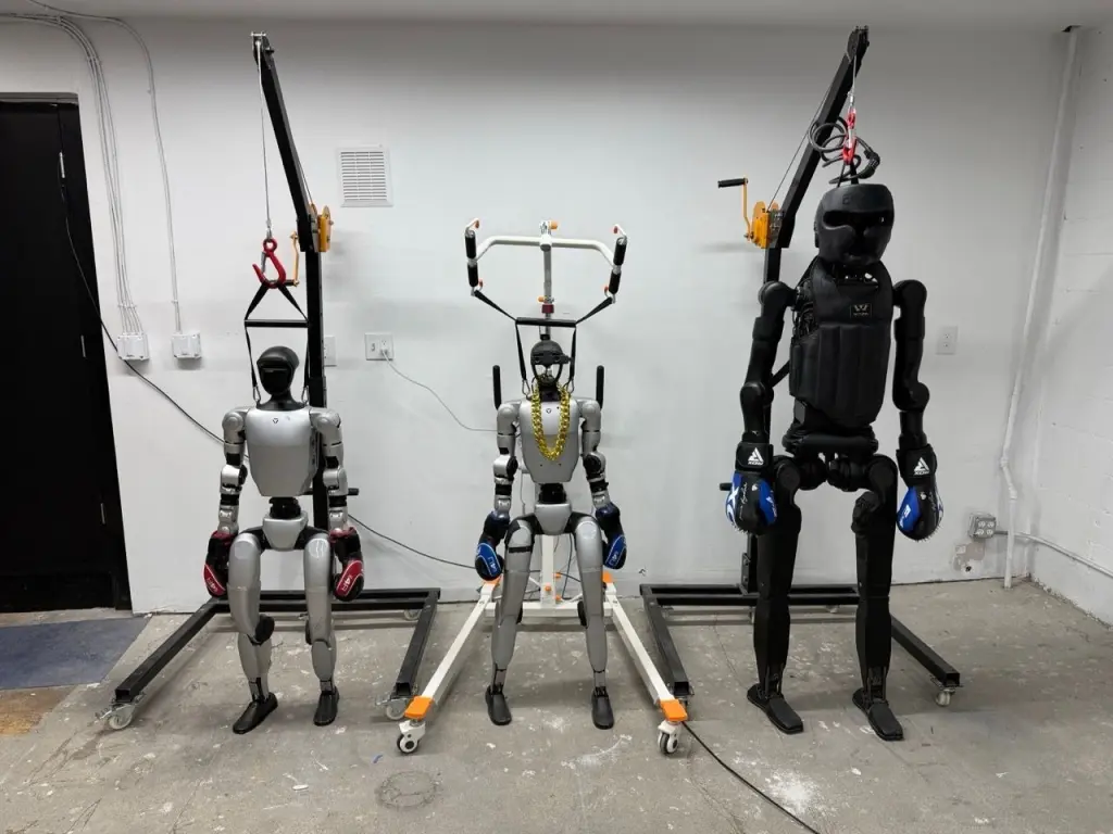 REK humanoid robots in a workshop setup with training rigs and boxing gloves